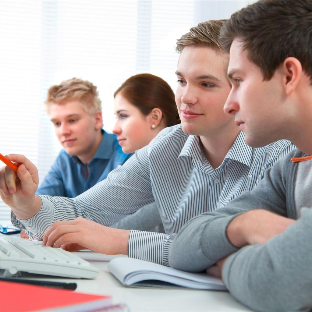 2 jugendliche Männer sitzen vor einem Bildschirm und besprechen eine Computeranwendung