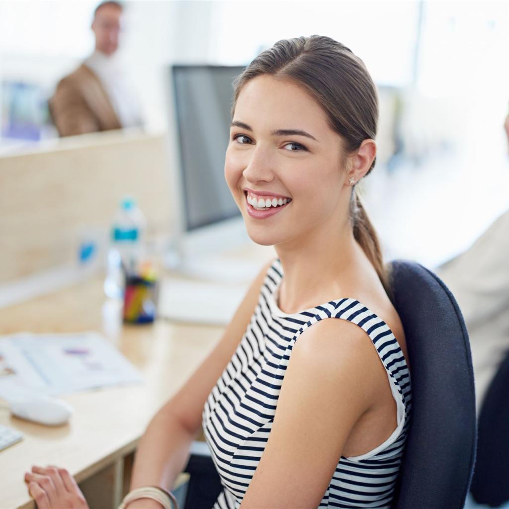 Eine junge Mitarbeiterin sitzt vor ihrem Computerbildschirm 