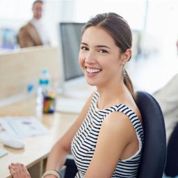 Eine junge Mitarbeiterin sitzt vor ihrem Computerbildschirm 