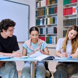 3 Studierende sitzen am Schreibtisch vor einem Laptop und lernen intensiv