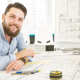 Ein junger Bauzeichner sitzt an seinem Schreibtisch