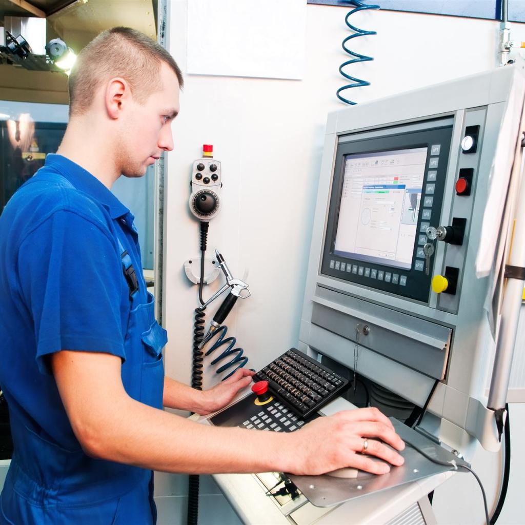 Ein junger Maschinenführer vor seinem Bedienpult